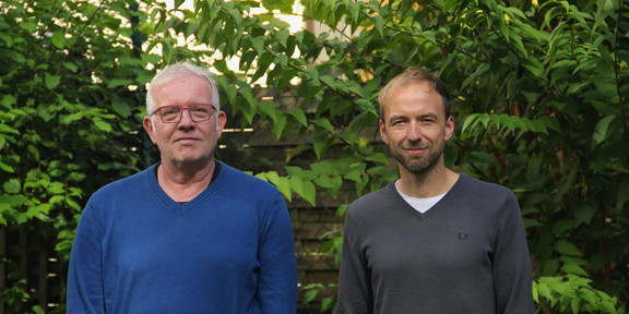 Portraitaufnahme: Andreas Seiler-Kesselheim (links) und Tobias Bernasconi (rechts) vor einem grünen Busch