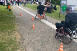 Rollstuhlparcour Foto. Zwei Menschen fahren im Rollstuhl durch den Rollstuhlparcour.