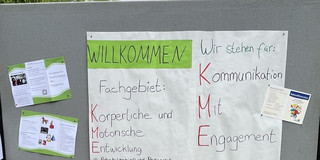 Foto. Stellwand mit Plakat "Willkommen: Fachgebiet Körperliche und Motorische Entwicklung in Rehabilitation und Pädagogik. Wir stehen für Kommunikation mit Engagement"und Flyern
