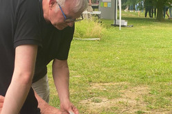 Selbsterfahrung beim Anreichen von Getränken Foto. Andreas Seiler-Kesselheim reicht einem liegenden Mann Getränk in Schnabeltasse an.
