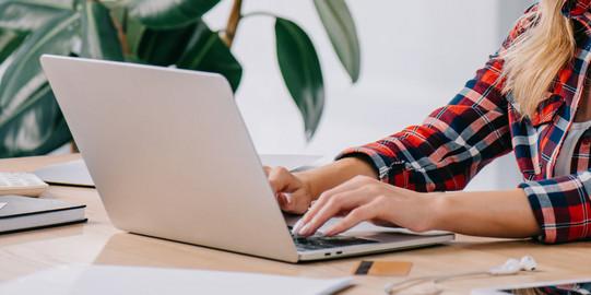 Frau sitzt vor einem Laptop und tippt
