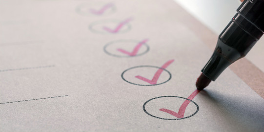 Checkliste eine Liste auf einem Klemmbrett, ein Stift hakt einzelne Felder ab